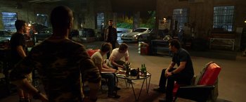 Movie still from “Need for Speed” (2014), directed by Scott Waugh – A group of people sitting around a table with drinks; Wide shot, High angle