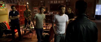 Movie still from “Need for Speed” (2014), directed by Scott Waugh – A group of young men standing around in a room; Medium shot, Over the shoulder angle