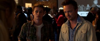 Movie still from “Need for Speed” (2014), directed by Scott Waugh – Two men standing next to each other at a party; Close Up shot, Over the shoulder angle