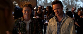 Movie still from “Need for Speed” (2014), directed by Scott Waugh – Two men standing next to each other in front of a crowd; Medium shot, Low angle