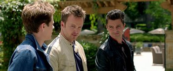 Movie still from “Need for Speed” (2014), directed by Scott Waugh – A group of men standing next to each other in front of trees; Close Up shot, Over the shoulder angle
