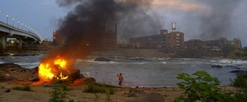 Movie still from “Need for Speed” (2014), directed by Scott Waugh – A man standing on a beach near a body of water; Extreme Wide shot, High angle