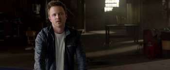 Movie still from “Need for Speed” (2014), directed by Scott Waugh – A man wearing a leather jacket standing in a dark room; Close Up shot, Low angle