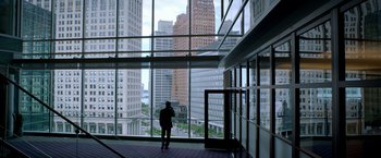 Movie still from “Need for Speed” (2014), directed by Scott Waugh – A man standing in front of a window looking out at a city skyline; Extreme Wide shot, Low angle