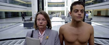 Movie still from “Need for Speed” (2014), directed by Scott Waugh – A man and a woman standing next to each other in a building; Close Up shot, Over the shoulder angle
