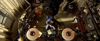 Movie still from “Need for Speed” (2014), directed by Scott Waugh – An overhead view of a man working on a computer; Wide shot, Overhead angle