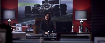 Movie still from “Need for Speed” (2014), directed by Scott Waugh – A woman sitting in front of a lap top computer; Medium shot, Over the shoulder angle