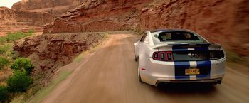 Movie still from “Need for Speed” (2014), directed by Scott Waugh – A car driving down a dirt road in the desert; Wide shot, Overhead angle