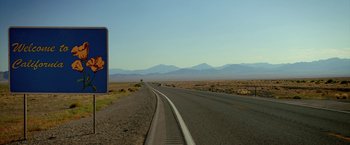 Movie still from “Need for Speed” (2014), directed by Scott Waugh – A road sign on the side of the road near the desert; Extreme Wide shot, Low angle