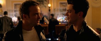 Movie still from “Need for Speed” (2014), directed by Scott Waugh – A couple of men standing next to each other in a room; Close Up shot, Over the shoulder angle