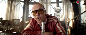 Movie still from “Need for Speed” (2014), directed by Scott Waugh – A man in a red and white leather jacket holding a microphone; Close Up shot, Low angle