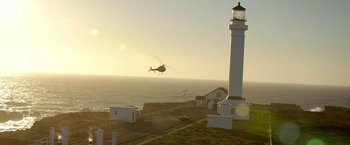 Movie still from “Need for Speed” (2014), directed by Scott Waugh – A helicopter flying near a lighthouse on the beach; Extreme Wide shot, Low angle