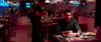 Movie still from “Nerve” (2016), directed by Henry Joost – A man sitting at a table in front of a counter; Medium shot, Over the shoulder angle