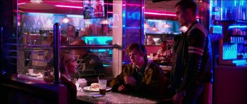 Movie still from “Nerve” (2016), directed by Henry Joost – A man sitting at a table in front of a plate of food; Medium shot, Over the shoulder angle