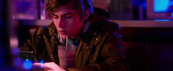 Movie still from “Nerve” (2016), directed by Henry Joost – A young man sitting down with a drink in his hand; Close Up shot, Over the shoulder angle