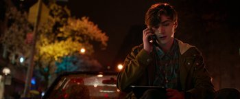 Movie still from “Nerve” (2016), directed by Henry Joost – A man on a cell phone while holding an ipad; Medium shot, Over the shoulder angle