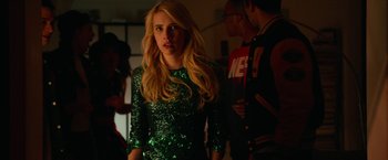 Movie still from “Nerve” (2016), directed by Henry Joost – A woman in a green dress standing in a room; Medium shot, Over the shoulder angle