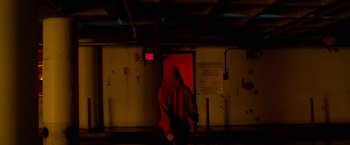 Movie still from “Nerve” (2016), directed by Henry Joost – A person in a red hoodie standing next to an exit sign; Wide shot, High angle