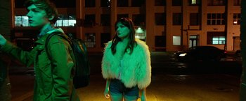 Movie still from “Nerve” (2016), directed by Henry Joost – A woman in a green jacket standing on the street; Medium shot, Over the shoulder angle