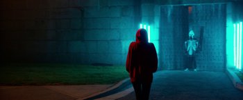 Movie still from “Nerve” (2016), directed by Henry Joost – A person wearing a hooded jacket walking in front of a building; Wide shot, Low angle