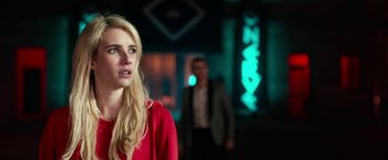 Movie still from “Nerve” (2016), directed by Henry Joost – A woman in a red shirt and a man in a black suit in the background; Close Up shot, Over the shoulder angle