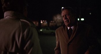 Movie still from “Network” (1976), directed by Sidney Lumet – An older man wearing a brown coat and a red tie; Medium shot, Over the shoulder angle