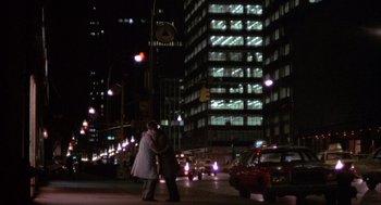 Movie still from “Network” (1976), directed by Sidney Lumet – A couple of people standing on a sidewalk at night; Extreme Wide shot, Over the shoulder angle