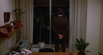 Movie still from “Network” (1976), directed by Sidney Lumet – A man standing in front of a window at night; Wide shot, High angle