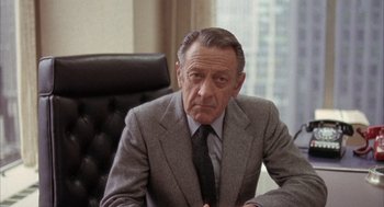 Movie still from “Network” (1976), directed by Sidney Lumet – An older man wearing a suit and tie sitting in a chair; Close Up shot, Over the shoulder angle