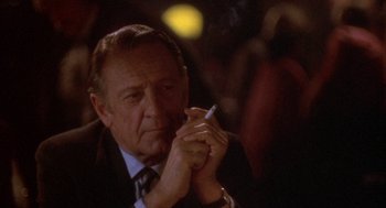 Movie still from “Network” (1976), directed by Sidney Lumet – An older man smoking a cigarette while sitting in a chair; Close Up shot, Over the shoulder angle