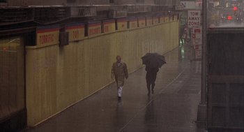Movie still from “Network” (1976), directed by Sidney Lumet – Two people walking in the rain with an umbrella; Wide shot, High angle