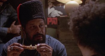 Movie still from “Network” (1976), directed by Sidney Lumet – A man with a beard is eating a piece of food; Close Up shot, Over the shoulder angle