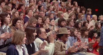 Movie still from “Network” (1976), directed by Sidney Lumet – A group of people sitting in a crowd clapping; Medium shot, High angle