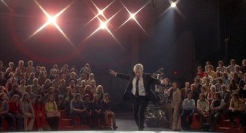 Movie still from “Network” (1976), directed by Sidney Lumet – A man in a suit and tie on a runway; Wide shot, Low angle