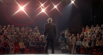 Movie still from “Network” (1976), directed by Sidney Lumet – A crowd of people watching a man on stage; Wide shot, Low angle