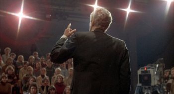 Movie still from “Network” (1976), directed by Sidney Lumet – A man giving a presentation to a crowd of people; Medium shot, High angle