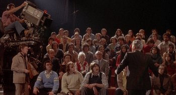 Movie still from “Network” (1976), directed by Sidney Lumet – A group of people sitting in front of an audience; Wide shot, High angle