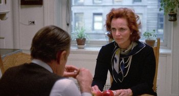 Movie still from “Network” (1976), directed by Sidney Lumet – A woman sitting at a table with an apple in front of a man; Medium shot, Over the shoulder angle