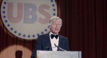 Movie still from “Network” (1976), directed by Sidney Lumet – An older man in a suit is speaking at a podium; Close Up shot, High angle