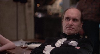 Movie still from “Network” (1976), directed by Sidney Lumet – A man sitting at a table with a glass of wine in front of him; Close Up shot, Low angle
