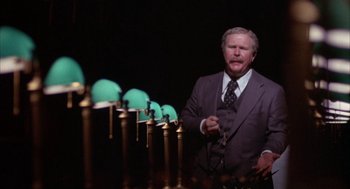 Movie still from “Network” (1976), directed by Sidney Lumet – A man standing in front of a row of bullets; Medium shot, Low angle