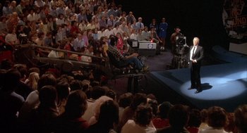 Movie still from “Network” (1976), directed by Sidney Lumet – A crowd of people sitting in front of an audience on a stage; Wide shot, High angle