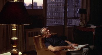 Movie still from “Network” (1976), directed by Sidney Lumet – An older man sitting in an arm chair in a living room; Medium shot, High angle