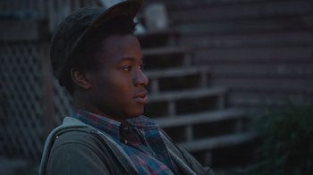 A young man wearing a hat and a plaid shirt