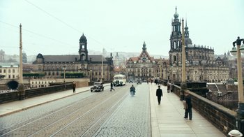 Movie still from “Never Look Away” (2018), directed by Florian Henckel von Donnersmarck – People are walking down the street on a rainy day; Extreme Wide shot, High angle