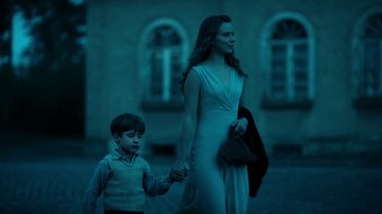 Movie still from “Never Look Away” (2018), directed by Florian Henckel von Donnersmarck – A woman and a boy holding hands while walking in the dark; Medium shot, Low angle