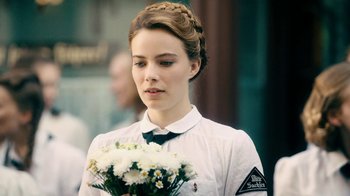 Movie still from “Never Look Away” (2018), directed by Florian Henckel von Donnersmarck – A young woman holding a bouquet of flowers; Close Up shot, Over the shoulder angle