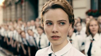 Movie still from “Never Look Away” (2018), directed by Florian Henckel von Donnersmarck – A woman with a braid in front of a group of people; Close Up shot, Over the shoulder angle