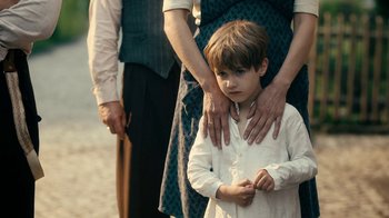 Movie still from “Never Look Away” (2018), directed by Florian Henckel von Donnersmarck – A young boy standing next to an older woman; Medium shot, Over the shoulder angle