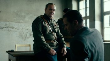 Movie still from “Never Look Away” (2018), directed by Florian Henckel von Donnersmarck – A man in a uniform sitting next to another man in a uniform; Medium shot, Over the shoulder angle